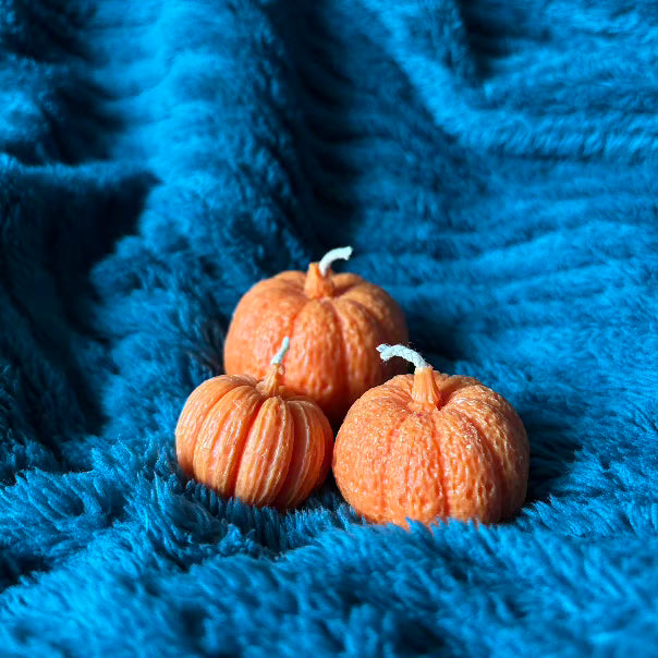 trio de bougies en cire végétale orange entassés 3 formats différents sur couverture fluffy vert canard incitant à la douceur
