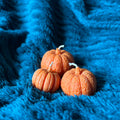 trio de bougies en cire végétale orange entassés 3 formats différents sur couverture fluffy vert canard incitant à la douceur